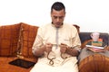 Muslim man using misbaha to keep track of counting in tasbih and drinking coffee, reading books Royalty Free Stock Photo