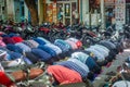 Muslim men in the masks bending down while praying at the street during covid-19 pandemic