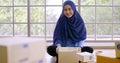 Happy muslim merchandiser woman holding parcel box in the office