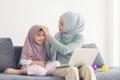 Muslim mom in hijab is her little daughter with computer sitting in the living room, Loving Relationship Royalty Free Stock Photo