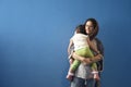 Muslim mother embraced slept little girl in front of blue wall background