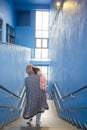 Muslim mother embraced slept little girl and going down from steps in blue building