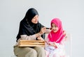 Muslim mother and her daughter are enjoin with cosmetic activity together in the room with white background and copy space Royalty Free Stock Photo