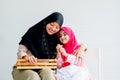 Muslim mother and her daughter are enjoin with cosmetic activity together in the room with white background and copy space Royalty Free Stock Photo