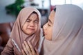 muslim Mother with hijab scarf comforting her crying little girl