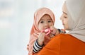 Muslim mother holding and hugging lovely cute innocent Muslim infant in hijab dress creeping with love and care