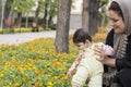 Muslim mother holding Little baby inside spring flowers at park, baby playing and touching flowers