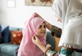 Muslim mother putting on a hijab on her little daughter