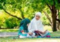 Muslim mother teach her daughter to read religion textbook for understanding the way of good life. They stay in the green garden