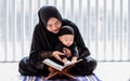 Muslim mother wearing traditional black dress and headscarf, carrying little baby boy, smiling, reading scripture, holding prayer Royalty Free Stock Photo