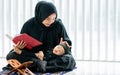 Muslim mother wearing traditional black dress and headscarf, carrying little boy, smiling, praying, reading scripture, taking baby Royalty Free Stock Photo