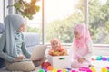 Muslim Mother working with laptop and Cute little baby playing toys in living room at home Royalty Free Stock Photo