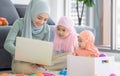 Muslim Mother working with laptop and Cute little baby playing toys in living room at home Royalty Free Stock Photo