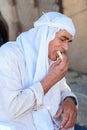 Muslim old man in ghutrah or keffiyeh or kufiya eat pita bread with hummus-traditional arab food.