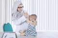 Muslim pediatrician checking her patient in the clinic