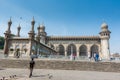 Muslim pilgrims walking into the Mecca Masjid mosque against blue sky and doves flying in sky, a famous monument in Hyderabad