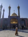 A Muslim scholar clergy walks past the golden dome of the Fatima Masuma shrine in Qom Qum