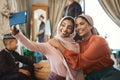 Muslim sisters taking selfies in traditional Islamic head scarf inside a happy family home together. Beautiful young Royalty Free Stock Photo