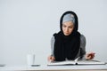 Muslim student sitting at the table and reading a book Royalty Free Stock Photo