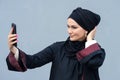 Muslim woman in black hijab makes selfies on smartphone