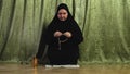 A Muslim woman in a black khimar reads prayer at home, fingering her rosary on the rug