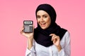 muslim woman with calculator and finance money pink background