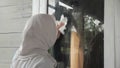 Muslim woman cleaning window glass with wag and spray