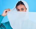 Muslim woman cover face with scarf in studio, blue background and color backdrop. Portrait, islamic female model and