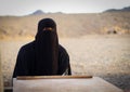 Muslim woman in a desert wearing a black hijab