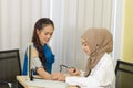 Muslim woman doctor using sphygmomanometer checking blood pressure to young asian patient in the hospital Royalty Free Stock Photo