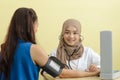 Muslim woman doctor using sphygmomanometer checking blood pressure to young asian patient in the hospital Royalty Free Stock Photo