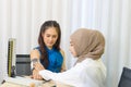 Muslim woman doctor using sphygmomanometer checking blood pressure to young asian patient in the hospital. Medicine and health Royalty Free Stock Photo