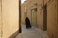 Muslim woman, dressed in black walk on the narrow street of old