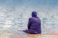 A Muslim woman dressed in a national costume for swimming sits on the seashore and looks into the distance