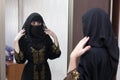 A Muslim woman dresses up in front mirror in her apartment