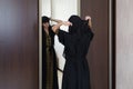 A Muslim woman dresses up front of a mirror