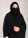 Muslim woman with face covered with burka holds thin fabric of yashmak with her hands