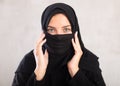 Muslim woman with face covered with burka holds thin fabric of yashmak with her hands