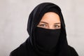 Muslim woman with face covered with burka holds thin fabric of yashmak with her hands