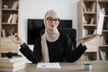 Muslim woman freelancer sitting at table with closed eyes and relieving stress by meditation Royalty Free Stock Photo