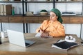 muslim woman in headkerchief writing in