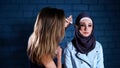 Muslim woman in hijab in beauty salon. Beautician applying makeup