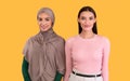 Muslim Woman And Caucasian Lady Posing Over Yellow Background Royalty Free Stock Photo