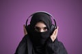 Muslim woman in hijab listening to music with wireless headset