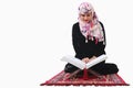 Muslim woman in hijab reading quaran holy book