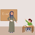 Muslim woman in hijab teaching physics in classroom where a girl student sits in a wheelchair