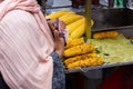 Muslim woman holding money and cellphone to buy corn on street stall