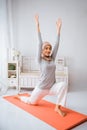 muslim woman instructor smiling wearing hijab anjaneyasana yoga pose pilates on mattress