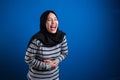 Muslim woman laughing hard while holding her belly, happy excited expression