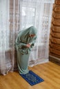 A Muslim woman in a light khimar performs Friday prayers at home